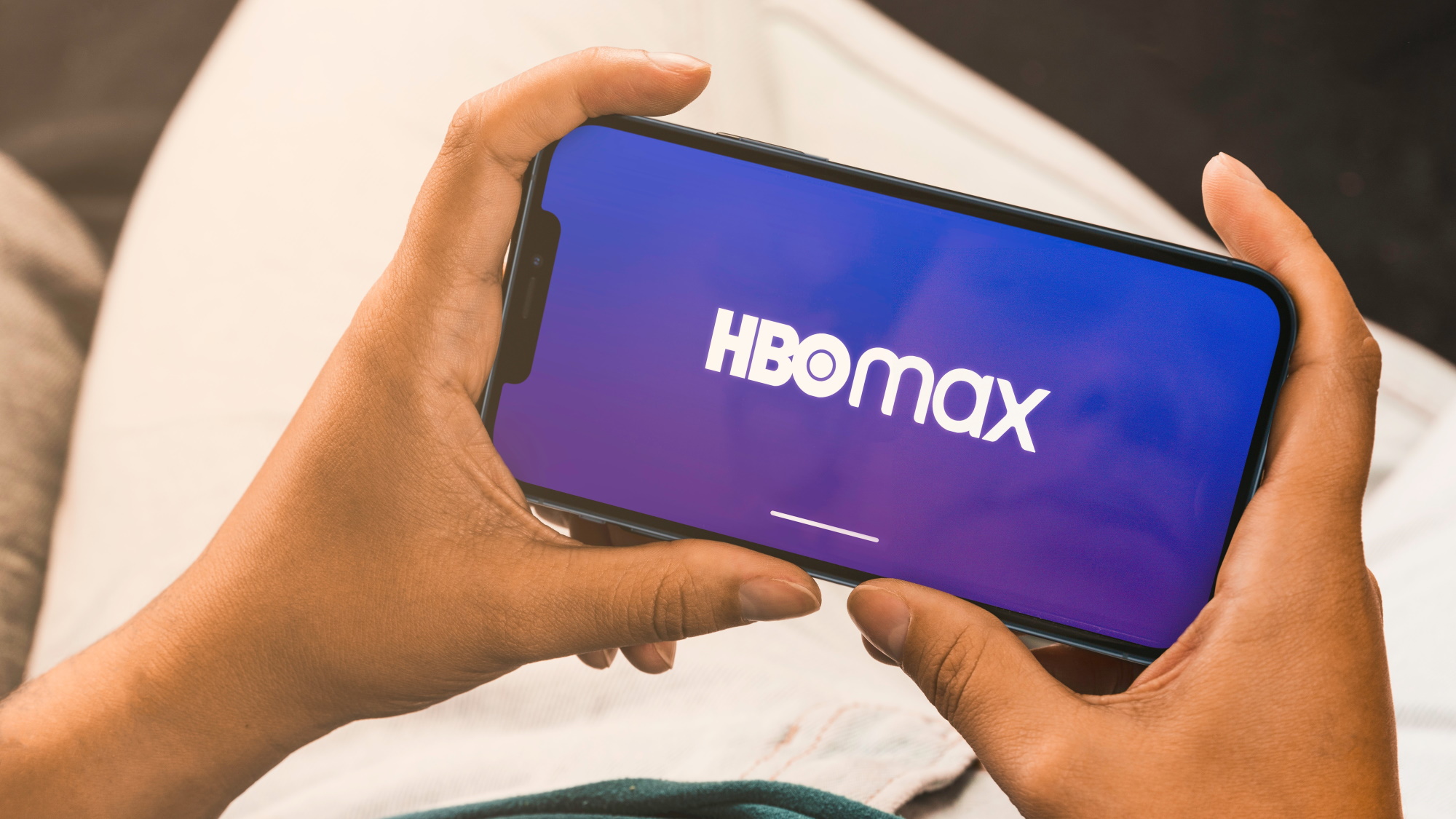 HBO Max logo on a smartphone being held by two hands