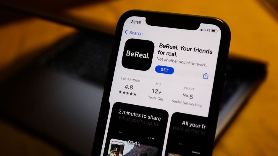 BeReal on the App Store displayed on a phone screen and a laptop in the background are seen in this illustration photo 