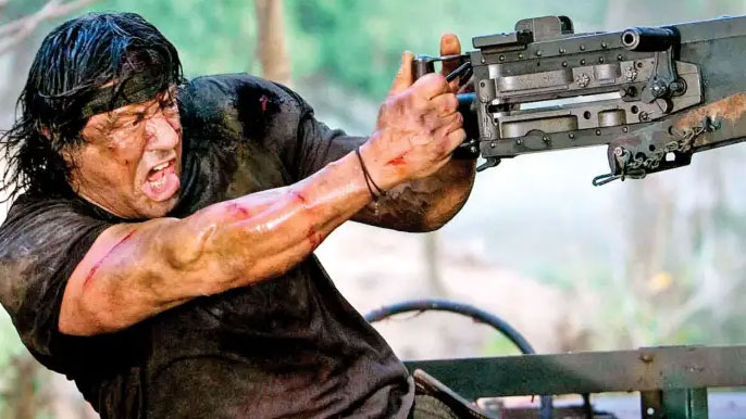 Sylvester Stallone is holding and gun and looking angry in this still from the movie Rambo