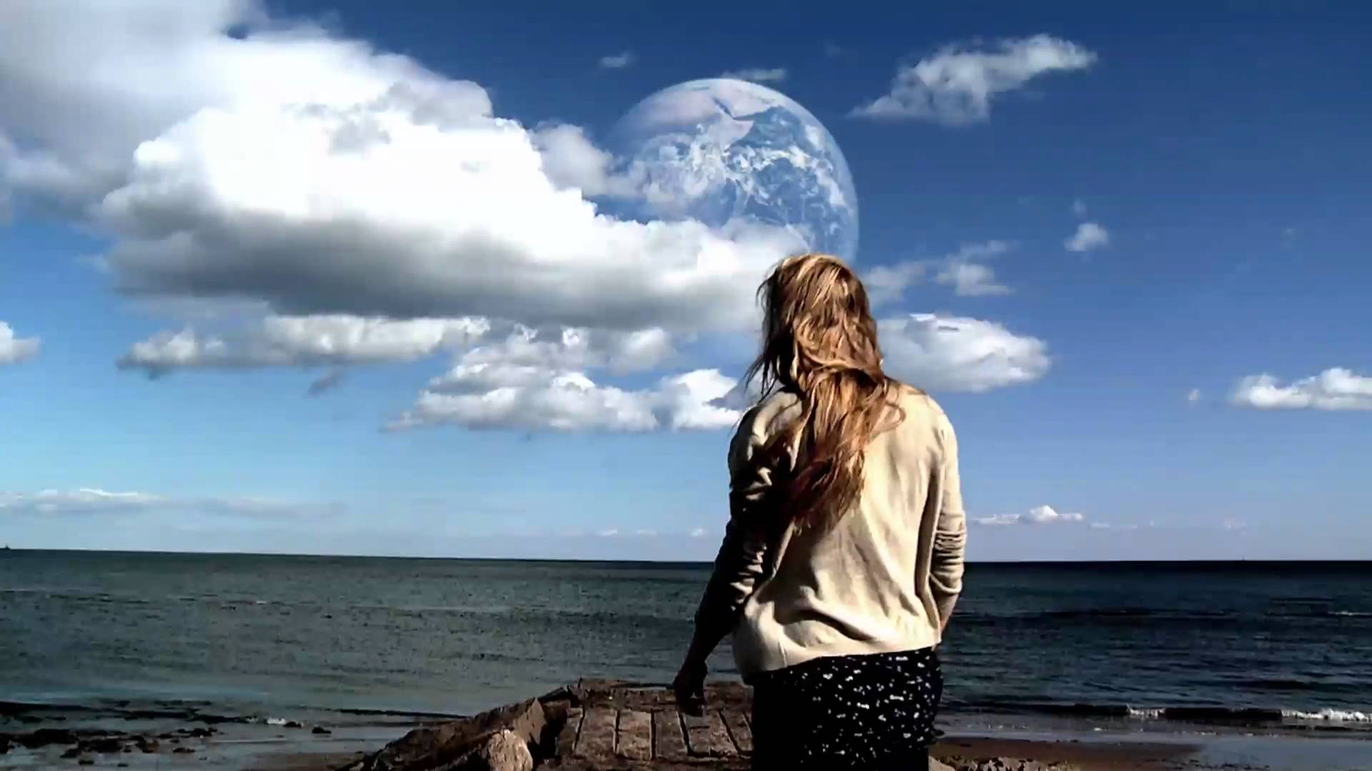 A still from the movie Another Earth in which the main character played by Britt Marling looks out over the sea to see Another Earth