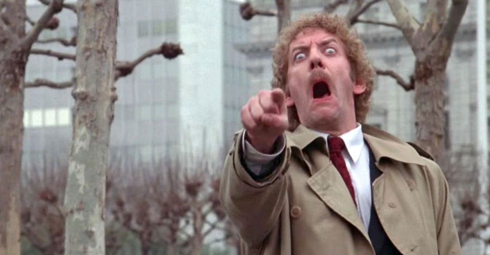 Donald Sutherland looks terrified pointing at the camera in a still from the movie Invasion of the Body Snatchers