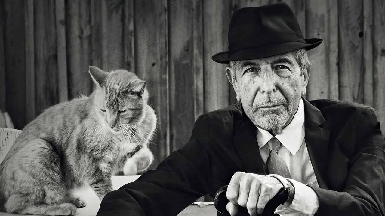 Leonard Cohen in suit and hat, next to cat